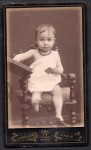 Portret bosej dziewczynki w foteliku Fotografia na kartoniku firmowym Paris [ca. 1885]
