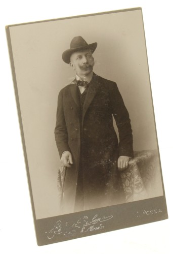 Portret mężczyzny w kapeluszu (Homburg), laska, podkręcony wąs Fotografia na tekturce firmowej / albumin (Poznań ca 1900 Rubens)