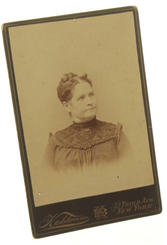 Portret kobiety, włosy upięte, popiersie, ciemna suknia, brosza Fotografia na tekturce firmowej / albumin (New York ca 1900 Kuhlmann)