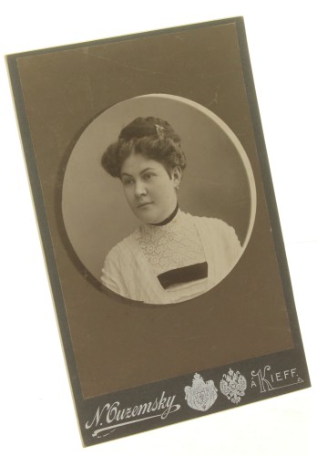 Portret kobiety, popiersie w okręgu, włosy upięte, suknia biała, aksamitka na szyi Fotografia na tekturce firmowej / odbitka srebrowożelatynowa (Kijów ca 1900 N. Ouzemsky)