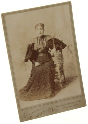 Portret kobiety, siedzący, ciemna suknia, bufiaste rękawy, włosy upięte Fotografia na tekturce firmowej / albumin (Dayton ca 1900 Grossman and Owings)