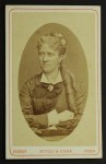 Portret kobiety, podkrążone smutne oczy, które dużo widziały, kolczyki, loki, upięcie ozdobione kwiatem Fotografia na tekturce /albumin [Rivoli & Comp/ Poznań ca 1880]