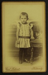 Portret dziecka, falbanki, kokardki, sukienka, buciki, krzesło Fotografia na tekturce /albumin [C. Rehmet/ Katowice ca 1880] 