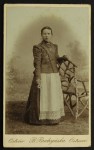 Portret kobiety, kwiatek, fartuszek, medalik, korale, krzesło Fotografia na tekturce /albumin [B. Budzyńska/ Ostrów ca 1880]