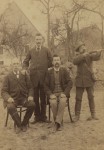 Portret mężczyzn w plenerze, dwóch siedzi, dwóch stoi, jeden w stroju myśliwego, z dwururką Fotografia na tekturce firmowej / albumin (Halle ca 1900 Josef Weissgerber)