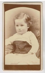 ​Portret dziewczynki - siedzący, biała sukienka, krótkie włosy Fotografia na kartoniku firmowym ca. 1900 / USA