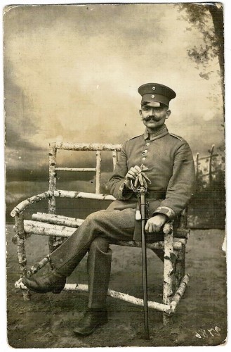 Pruski oficer wąsacz z szablą sympatyczny portret siedzący Fotografia na papierze pocztówkowym [ca 1916]
